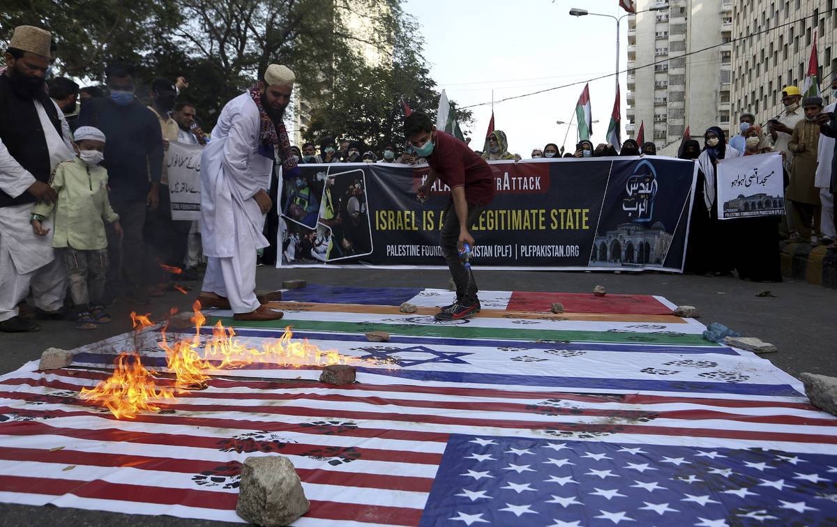 Members of a civil society group burn representations of Israeli, U.S. and Indian flags during ...