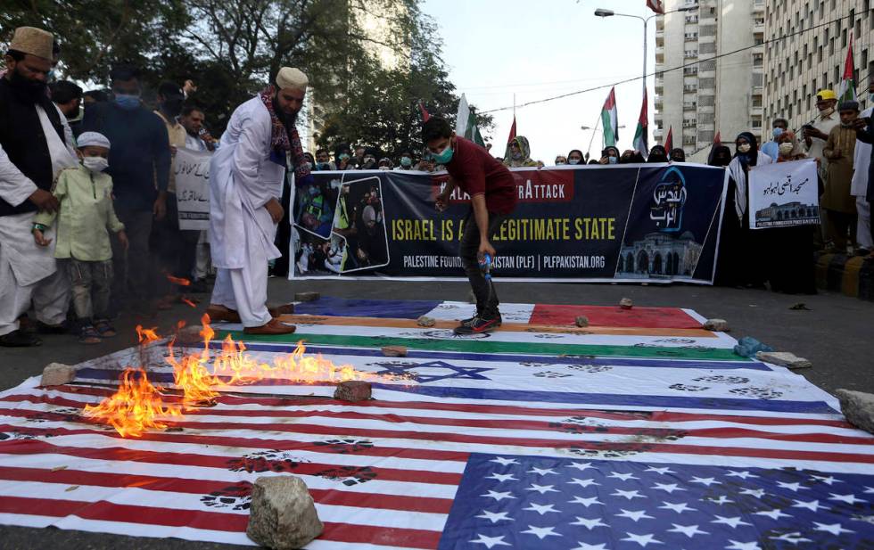 Members of a civil society group burn representations of Israeli, U.S. and Indian flags during ...