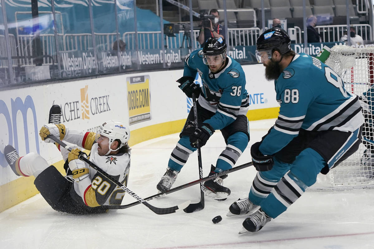 Vegas Golden Knights center Chandler Stephenson, left, reaches behind for the puck next to San ...