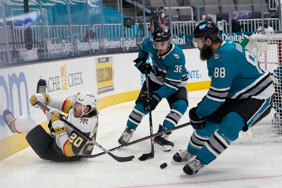 Vegas Golden Knights center Chandler Stephenson, left, reaches behind for the puck next to San ...