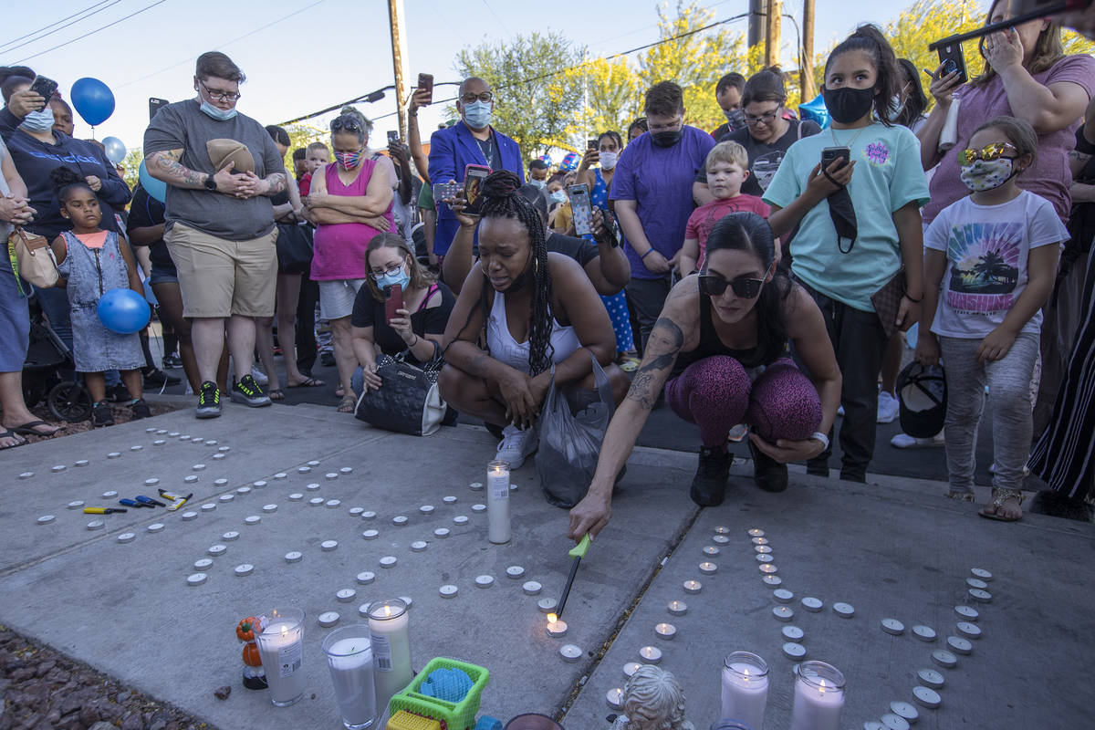 Andrea Sanchez, right, lights candles during a vigil for 2-year-old Amari Nicholson outside the ...