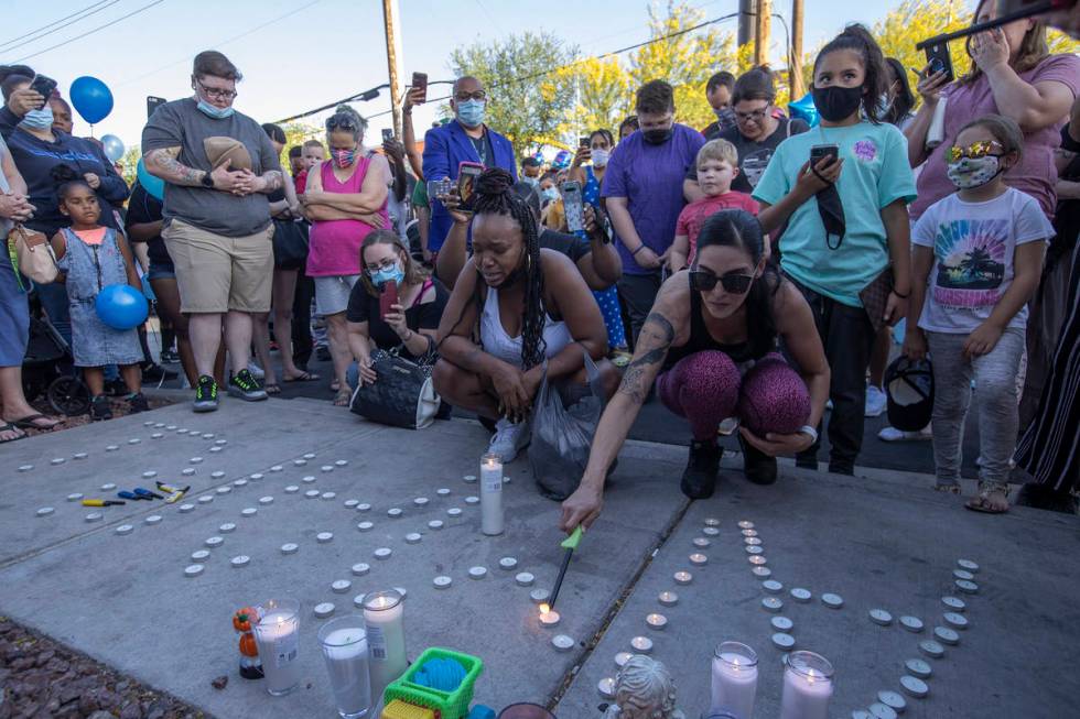 Andrea Sanchez, right, lights candles during a vigil for 2-year-old Amari Nicholson outside the ...