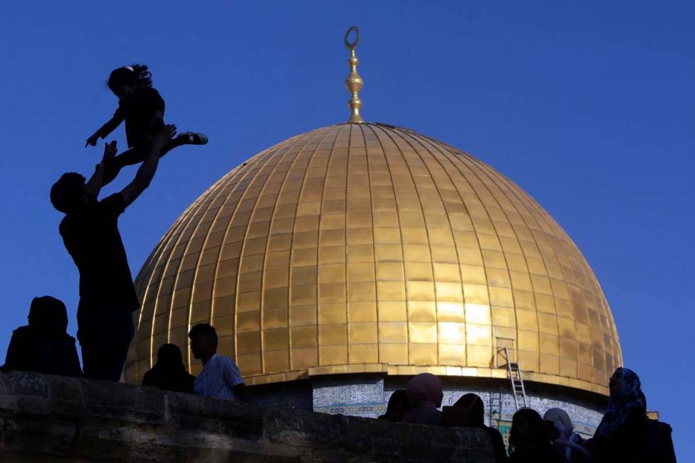 A girl is tossed into the air as people gather for Eid al-Fitr prayers at the Dome of the Rock ...