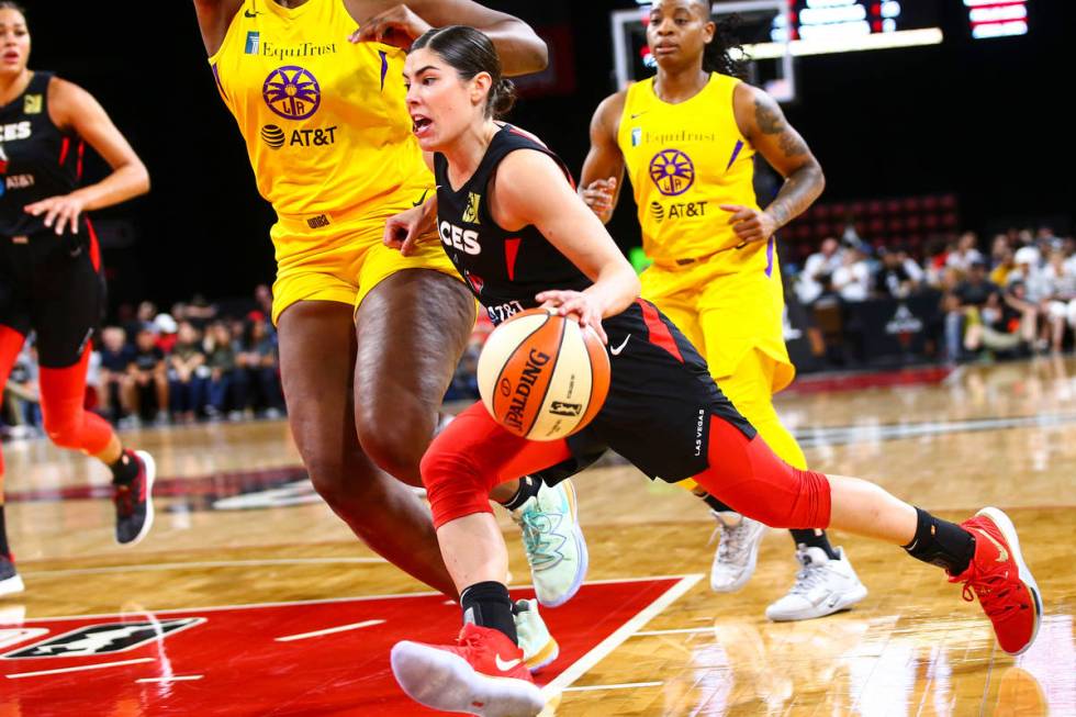 Las Vegas Aces' Kelsey Plum, center, drives to the basket against Los Angeles Sparks' Kalani Br ...