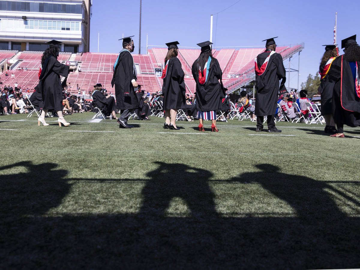 Family members shadows are seen as they take a picture of graduates during the first of several ...
