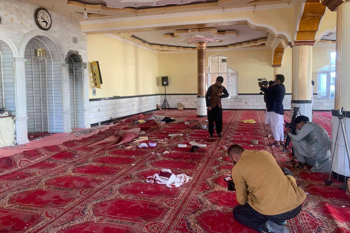 Afghan journalist take photos and film inside a mosque after a bomb explosion in Shakar Dara di ...