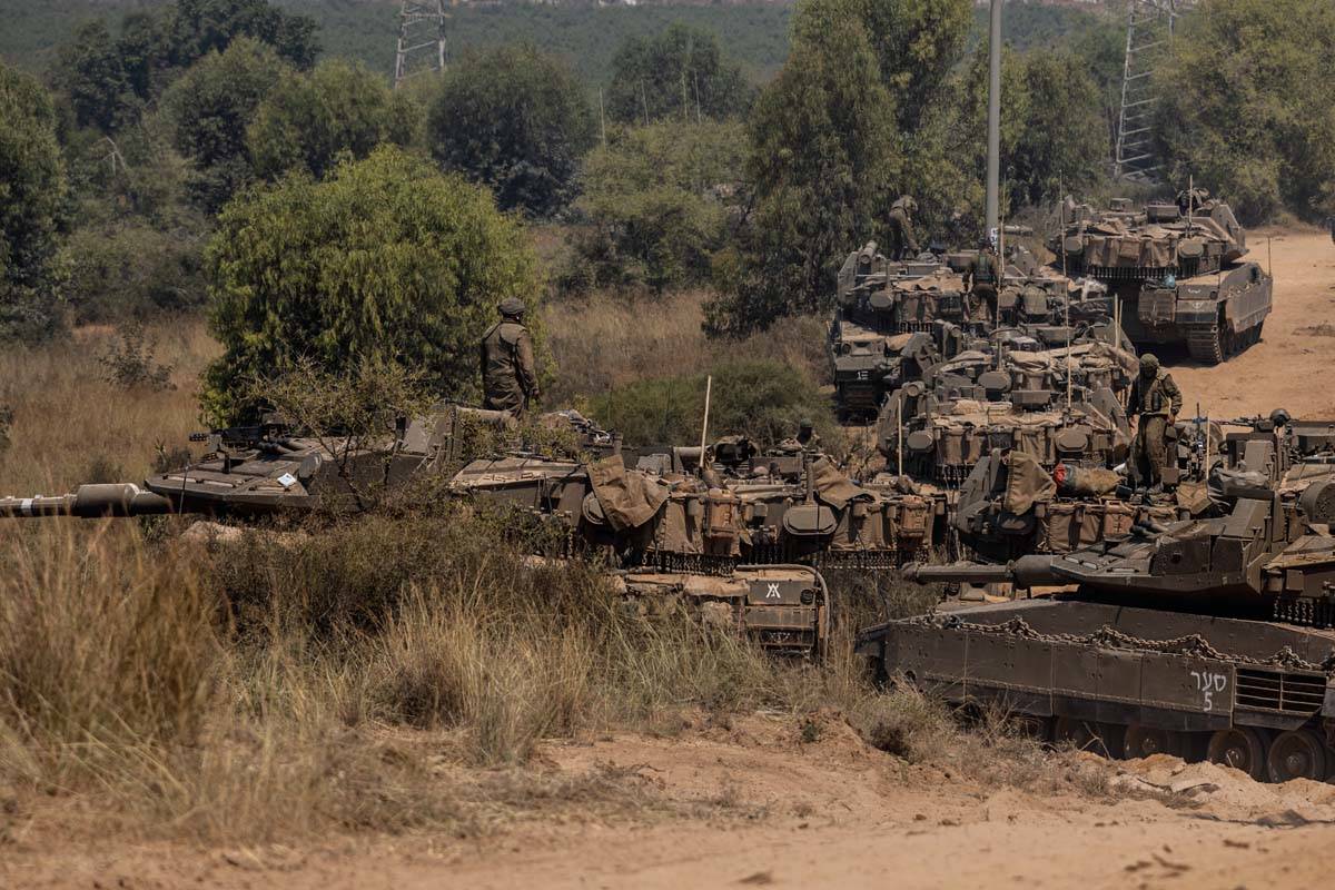 Israeli soldiers with armored vehicles gather in a staging ground near the border with Gaza Str ...