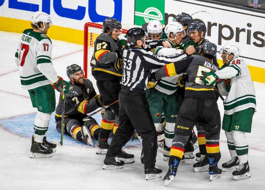 Golden Knights and Minnesota Wild players fight near the net during the third period of an NHL ...