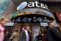 FILE - In this Oct. 21, 2014 file photo, people pass an AT&T store in New York's Times Squa ...