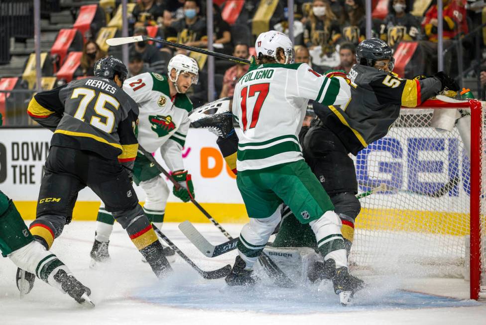 (From right) Golden Knights right wing Keegan Kolesar (55) is driven into the net by Minnesota ...