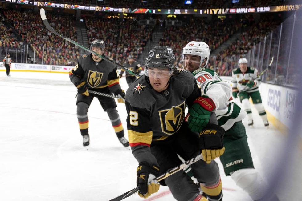 Golden Knights defenseman Zach Whitecloud (2) eyes the puck followed by Wild center Marcus Joha ...