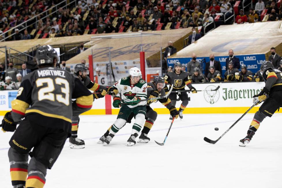 Wild left wing Kevin Fiala (22) and Golden Knights right wing Mark Stone (61), center, skate fo ...