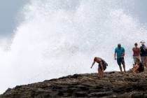 People react as a wave breaks off rocks in Laie, Hawaii, as Hurricane Douglas passed by the sta ...
