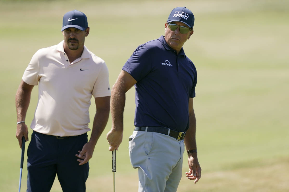 Brooks Koepka, left, and Phil Mickelson watch Mickelson putt on the fourth green during the fin ...