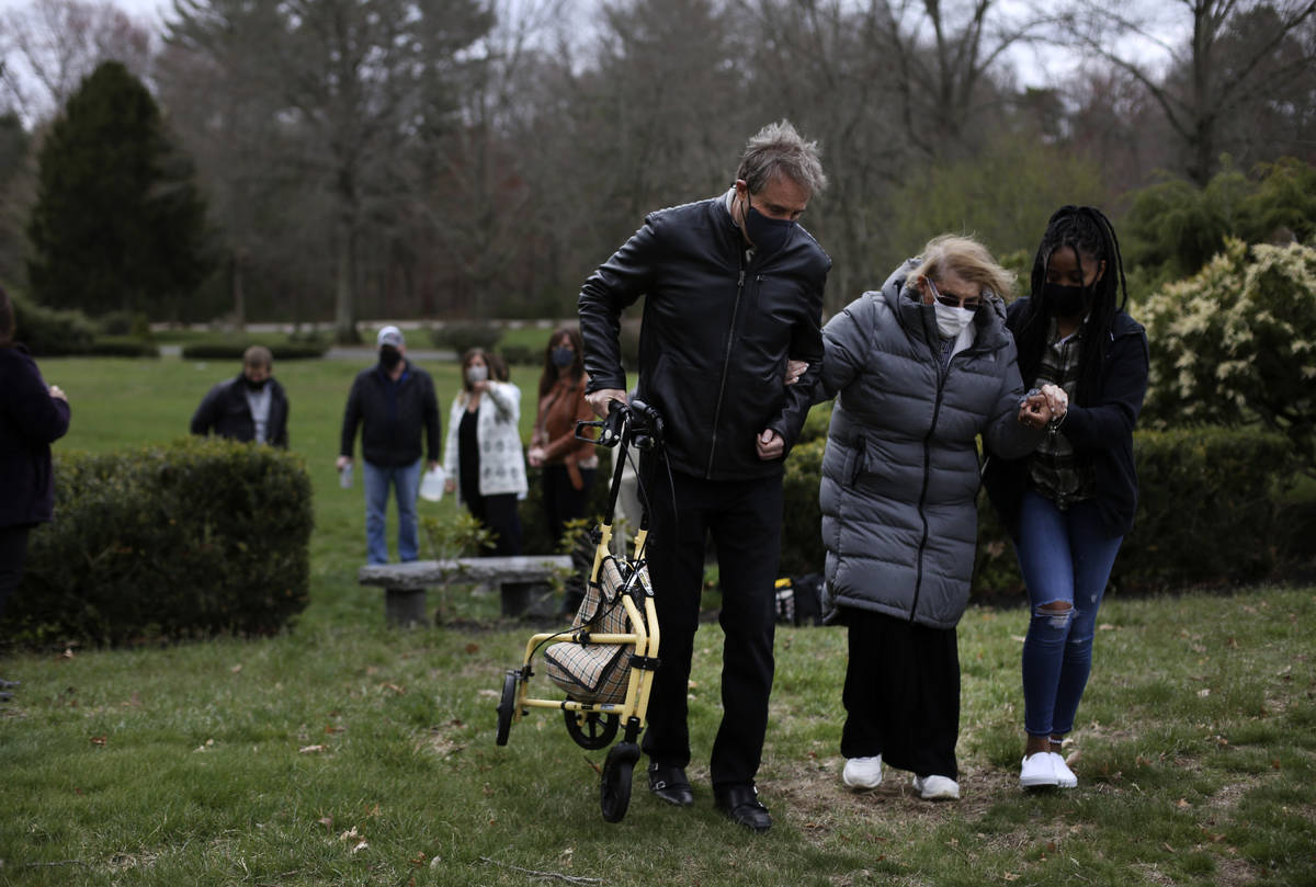 Larry Rubin, left, and Marcia Tavarez, a caregiver, right, helps his mother, Phyllis Rubin, cen ...