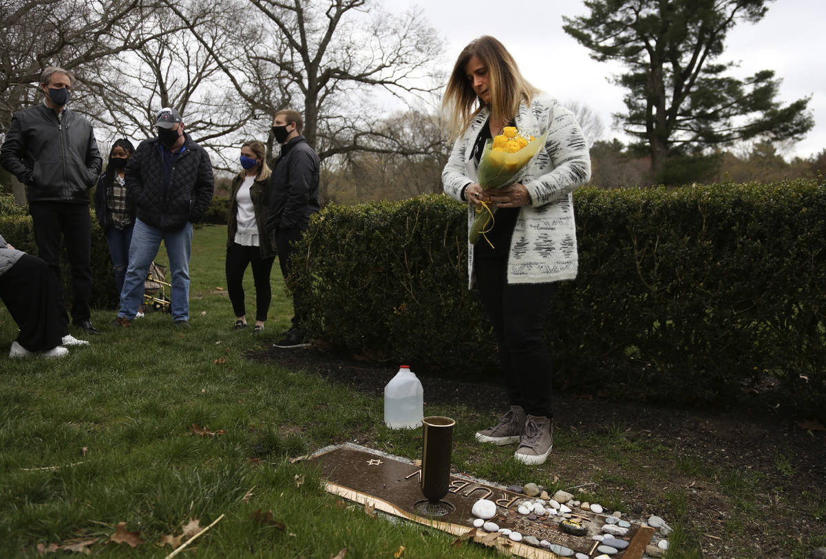 Michelle Pepe places a bouquet of yellow roses on her father's grave as family and friends watc ...