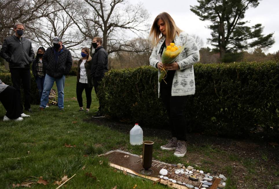 Michelle Pepe places a bouquet of yellow roses on her father's grave as family and friends watc ...