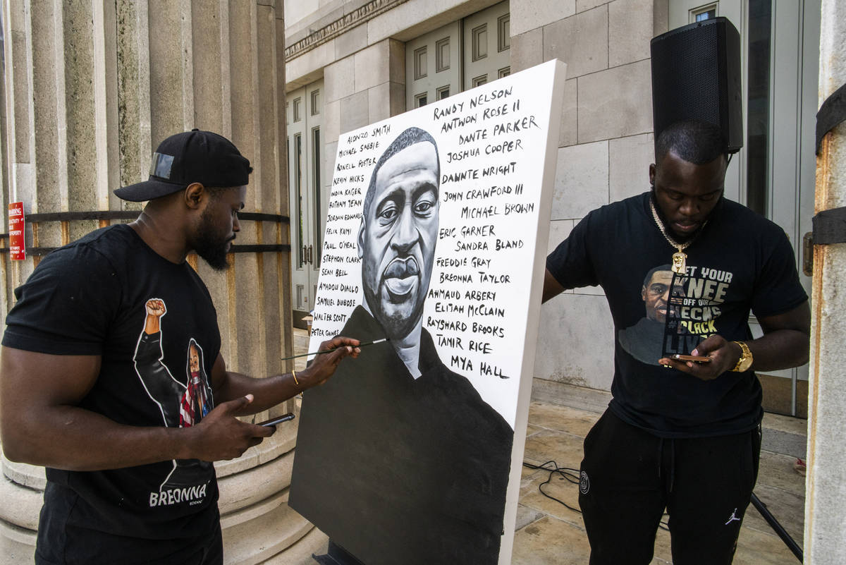 Artist Dennis Owes, 31, from Ghana gives the last touch to his portrait of George Floyd during ...