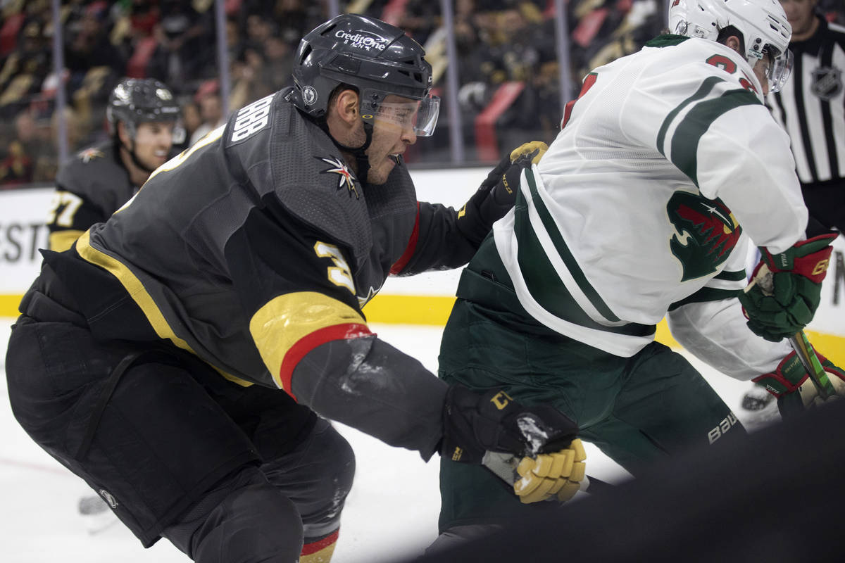 Golden Knights defenseman Brayden McNabb (3) slams Wild left wing Kevin Fiala (22) into the boa ...