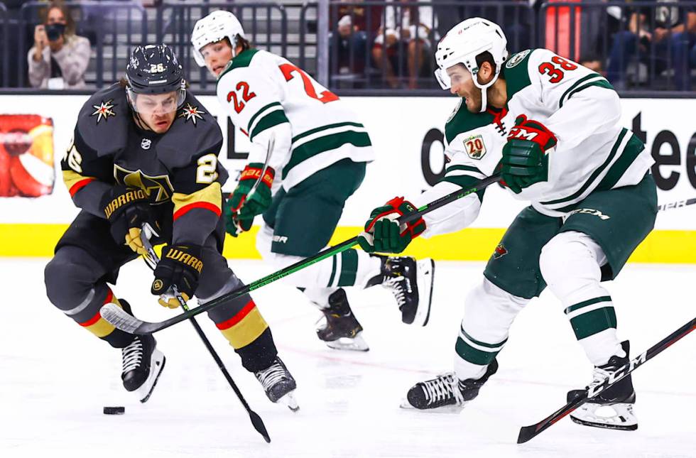 Golden Knights' Mattias Janmark (26) skates with the puck under pressure from Minnesota Wild's ...