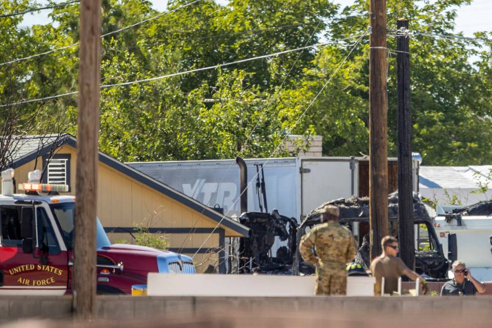 Military personnel look to a burned out vehicle near where a Nellis Air Force Base jet crashed ...