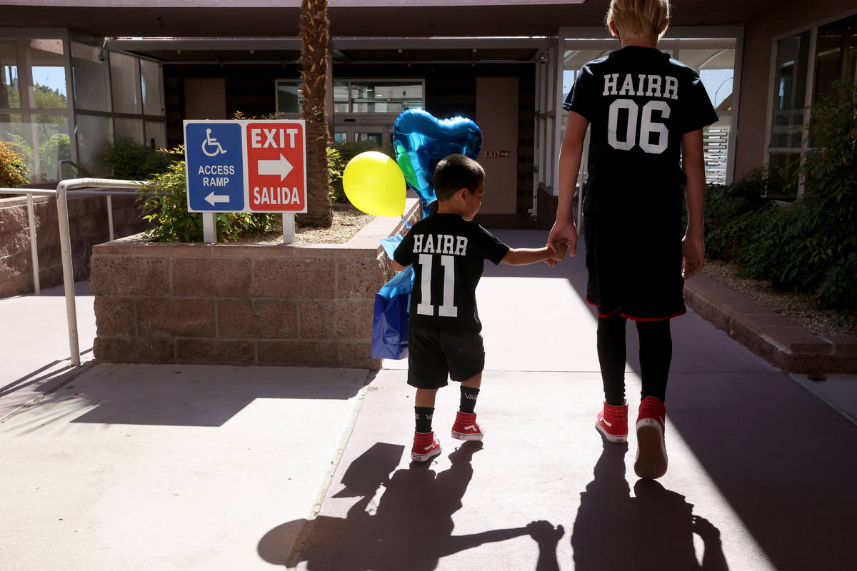 Jacob Heath Hairr, (#11) age 3, holds the hand of his brother James Heath Hairr, (#6) age 14, a ...