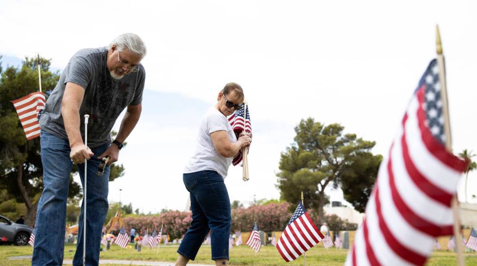 Garry Bordman and his wife Lori, both retired United States Air Force, place American flags, in ...