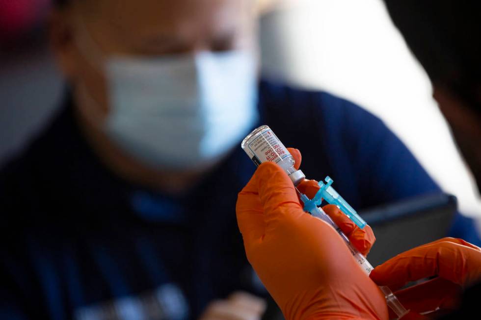 Paramedic Craig Johnson draws a dose of the Moderna COVID-19 vaccine in preparation for Guardia ...