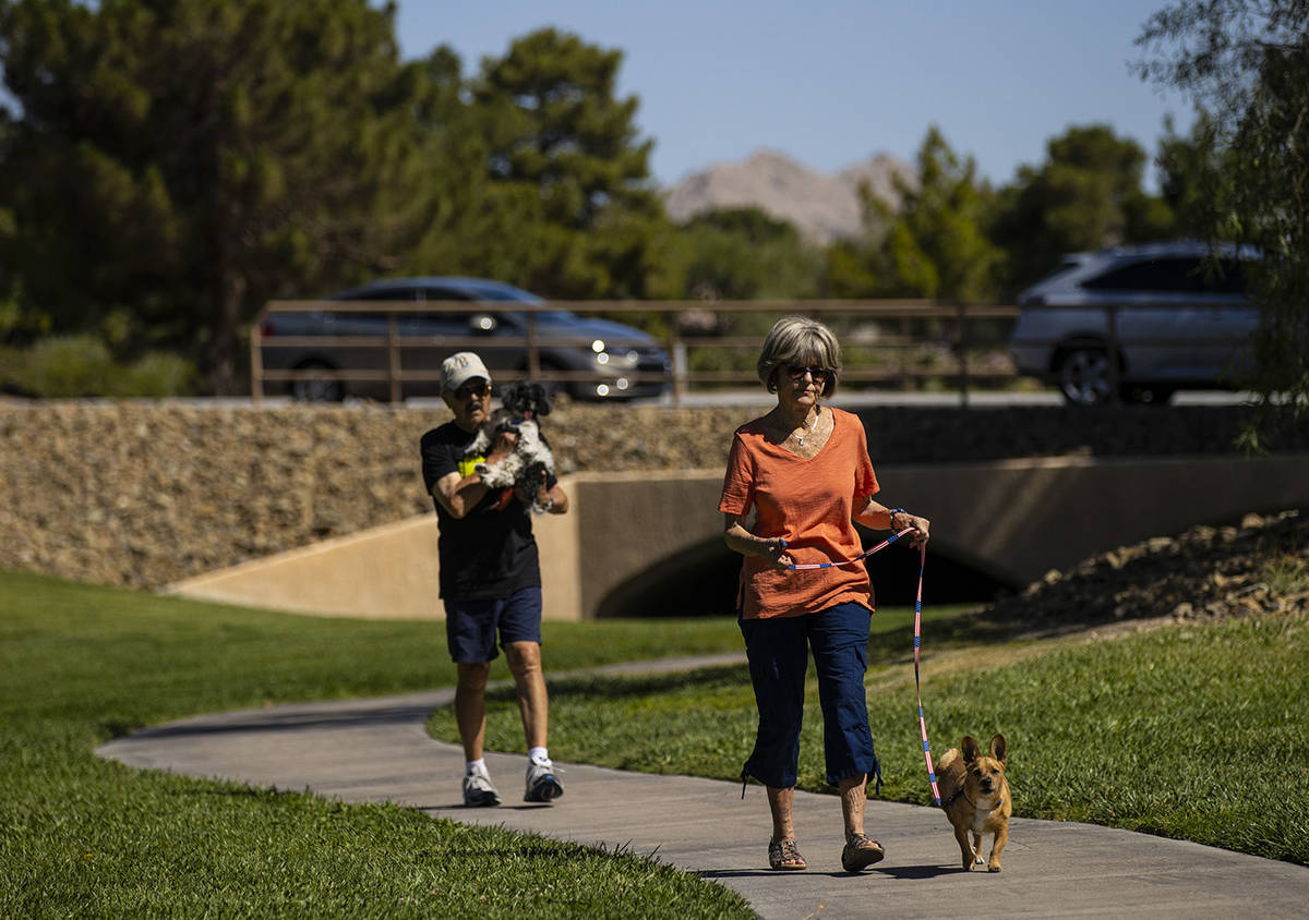 Carol Liberty walks her dog, Mikey, as Phil Sardo, carrying his dog, Mei Mei, walks behind in S ...