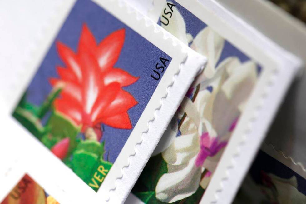 Stamps are attached to envelopes Friday, May 28, 2021, in Washington. The U.S. Postal Service i ...