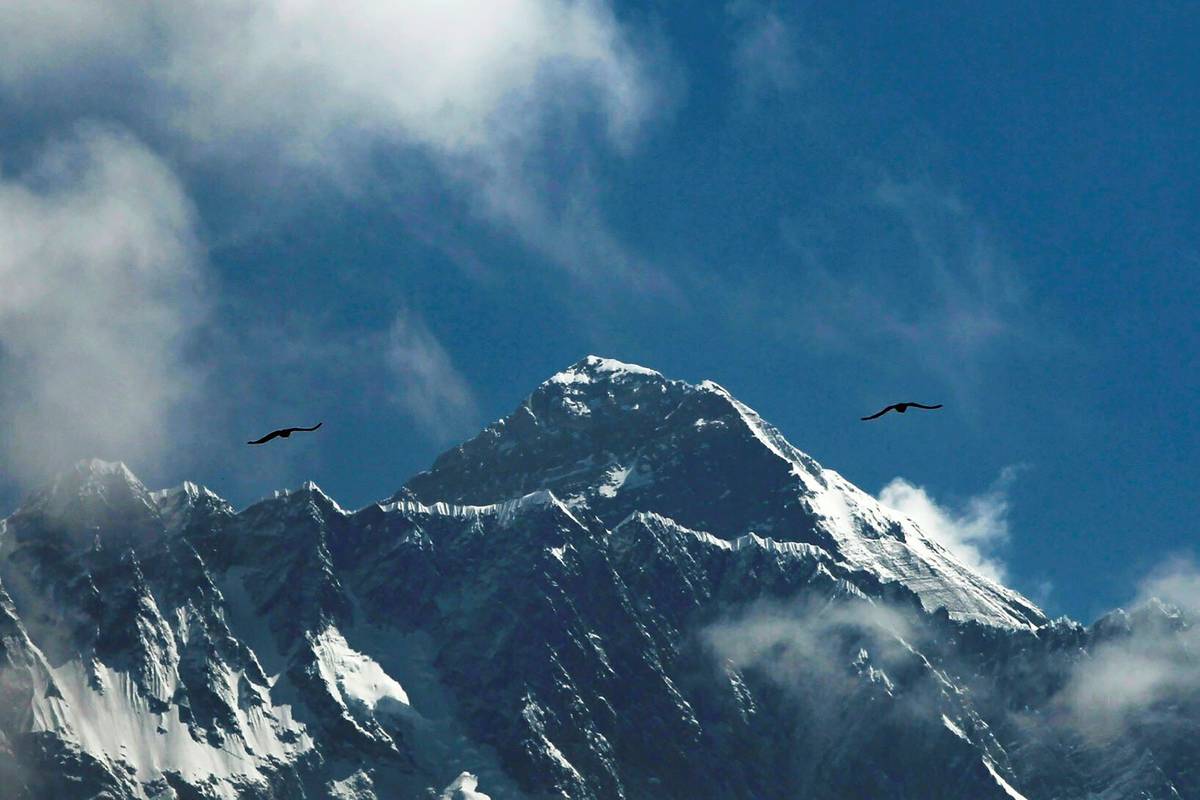 Birds fly as Mount Everest is seen from Namche Bajar, Solukhumbu district, Nepal, in May 2019. ...