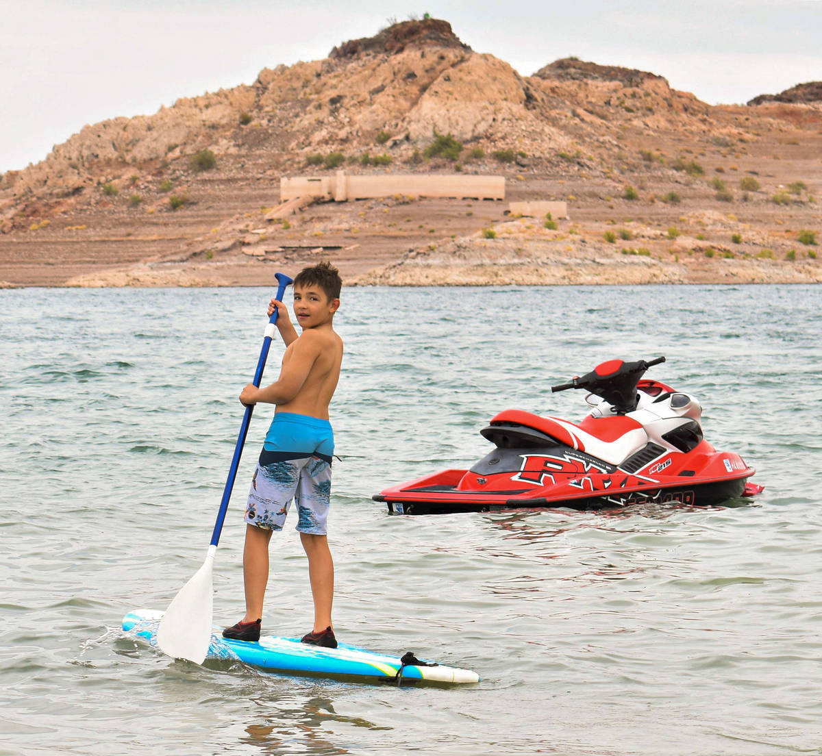 Zeke Varela, 10, looks back at his family as he shows off on the paddle board on Saturday, May ...