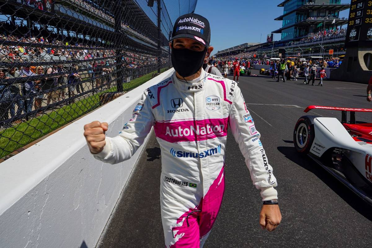 Helio Castroneves, of Brazil, gestures as he talks with fans on his way to his car before the I ...