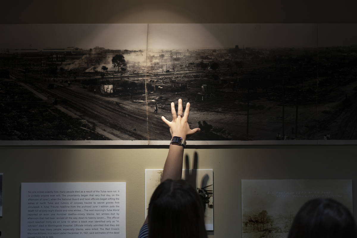 A woman points at a picture of devastation from the Tulsa Race Massacre in a prayer room dedica ...