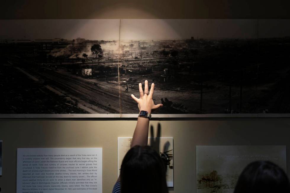 A woman points at a picture of devastation from the Tulsa Race Massacre in a prayer room dedica ...