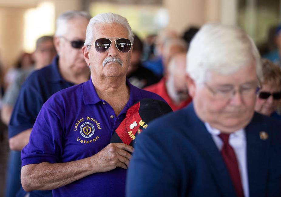 Vietnam veteran Mark Curley, left, stands during the playing of the national anthem during a Me ...