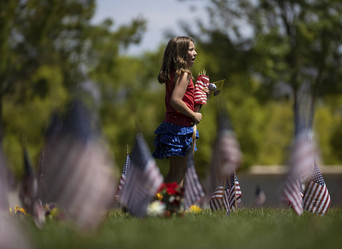 Volunteer Payton Finlayson, 8, helps collect flags from grave stones at the conclusion of a Mem ...