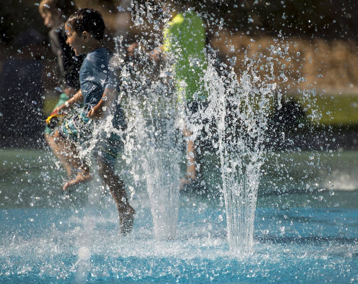 Leo Reyes, 3, runs through the water fountains as he stays cool on the splash pad at The Paseos ...