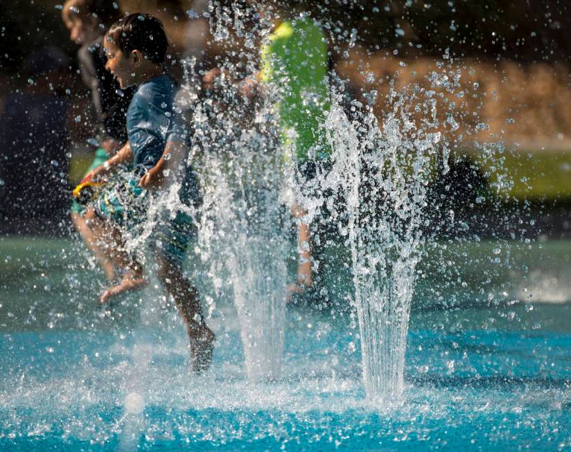 Leo Reyes, 3, runs through the water fountains as he stays cool on the splash pad at The Paseos ...