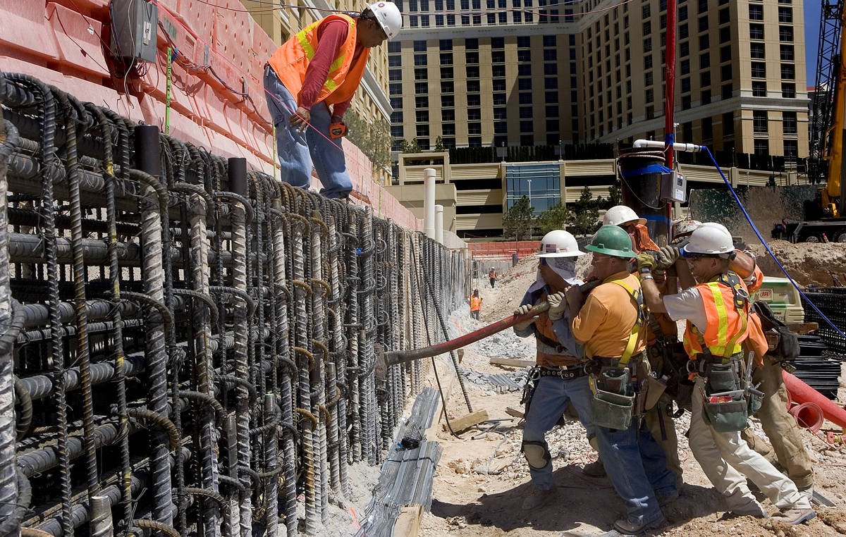 Perini Building Co. construction workers use a hickeybar to straighten a piece of rebar in the ...