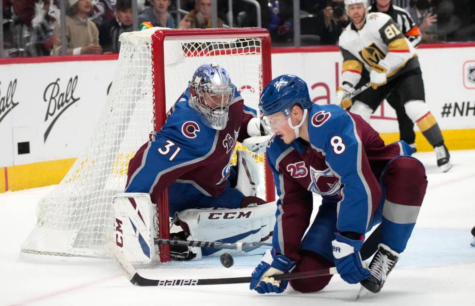 Colorado Avalanche defenseman Cale Makar, front, deflects a shot next to goaltender Philipp Gru ...