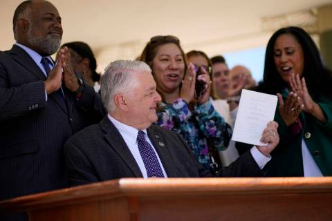 Nevada Democratic Gov. Steve Sisolak holds up a bill newly signed into law Friday, June 11, 202 ...