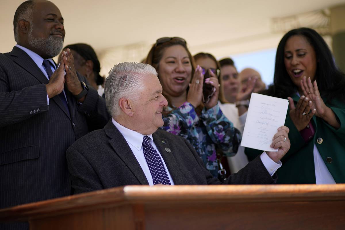 Nevada Democratic Gov. Steve Sisolak holds up a bill newly signed into law Friday, June 11, 202 ...