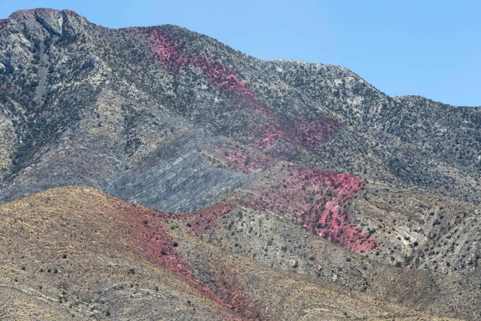 Fire retardant is present on the western slope of Potosi Mountain while crews battle the Sandy ...