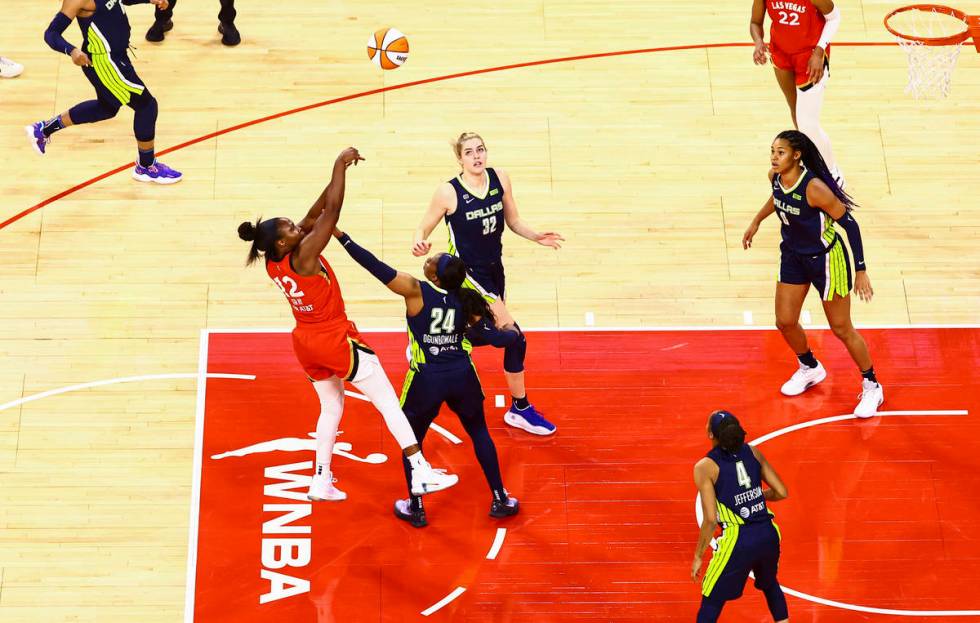 Las Vegas Aces' Chelsea Gray (12) shoots over Dallas Wings' Arike Ogunbowale (24) during the th ...