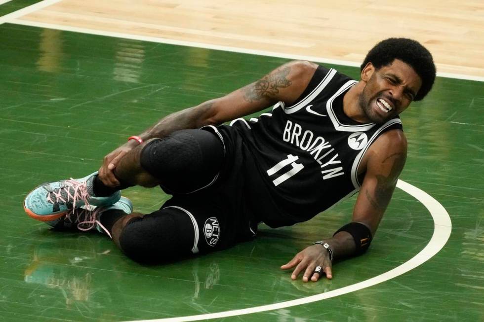 Brooklyn Nets' Kyrie Irving holds his leg after being injured during the first half of Game 4 o ...