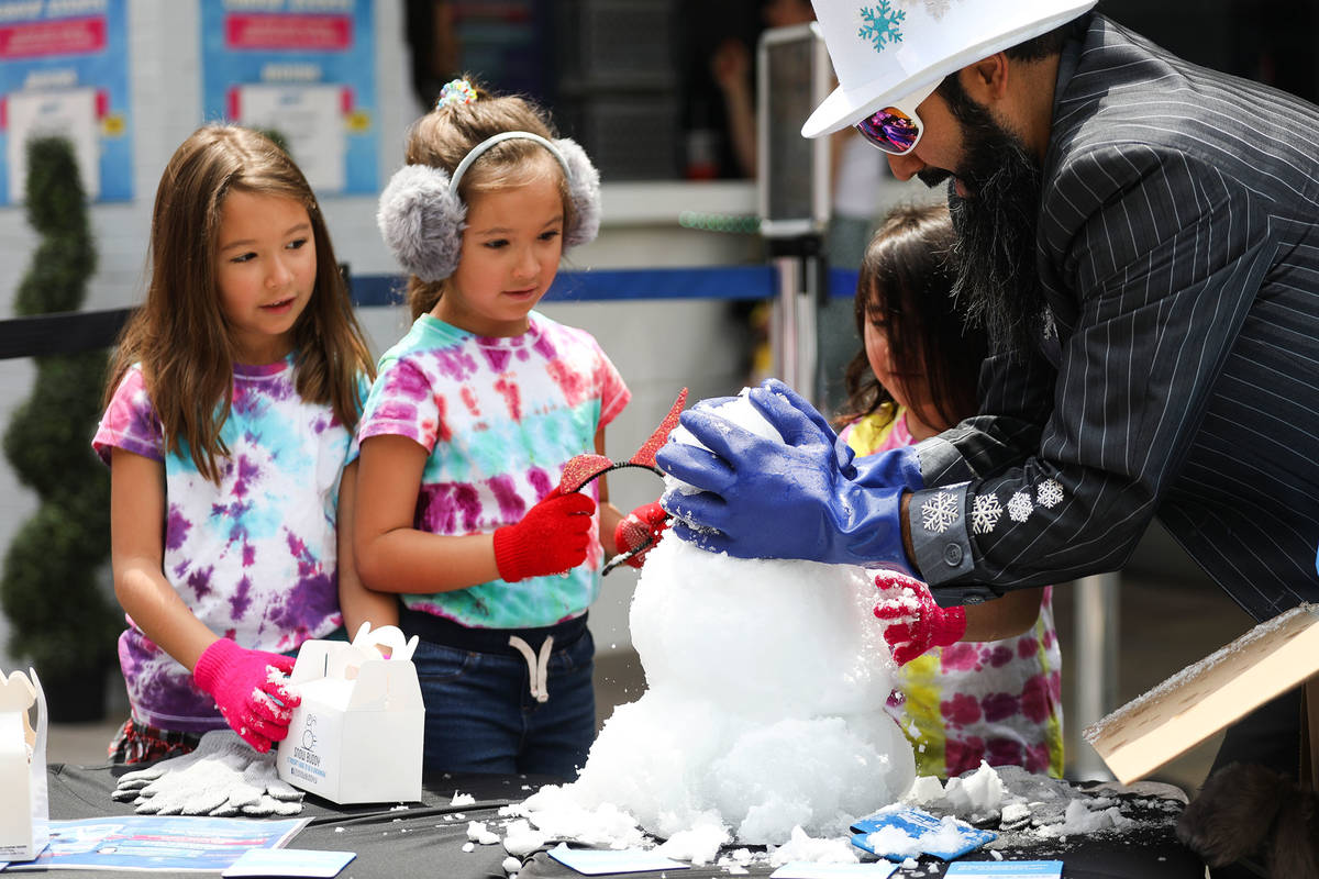 Marco Villarreal, known as "Vegas Ice Man," helps his daughters Mabel Villarreal, 7, left, and ...