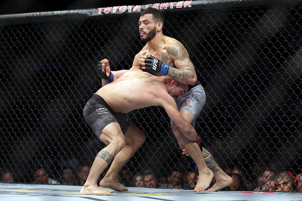 Mirsad Bektic, left, grabs the leg of Dan Ige during the first round of a featherweight mixed m ...
