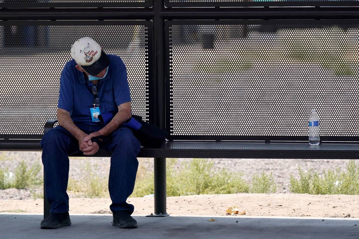 A person waits for a bus in the shade as the heat wave in the Western states continues Thursday ...