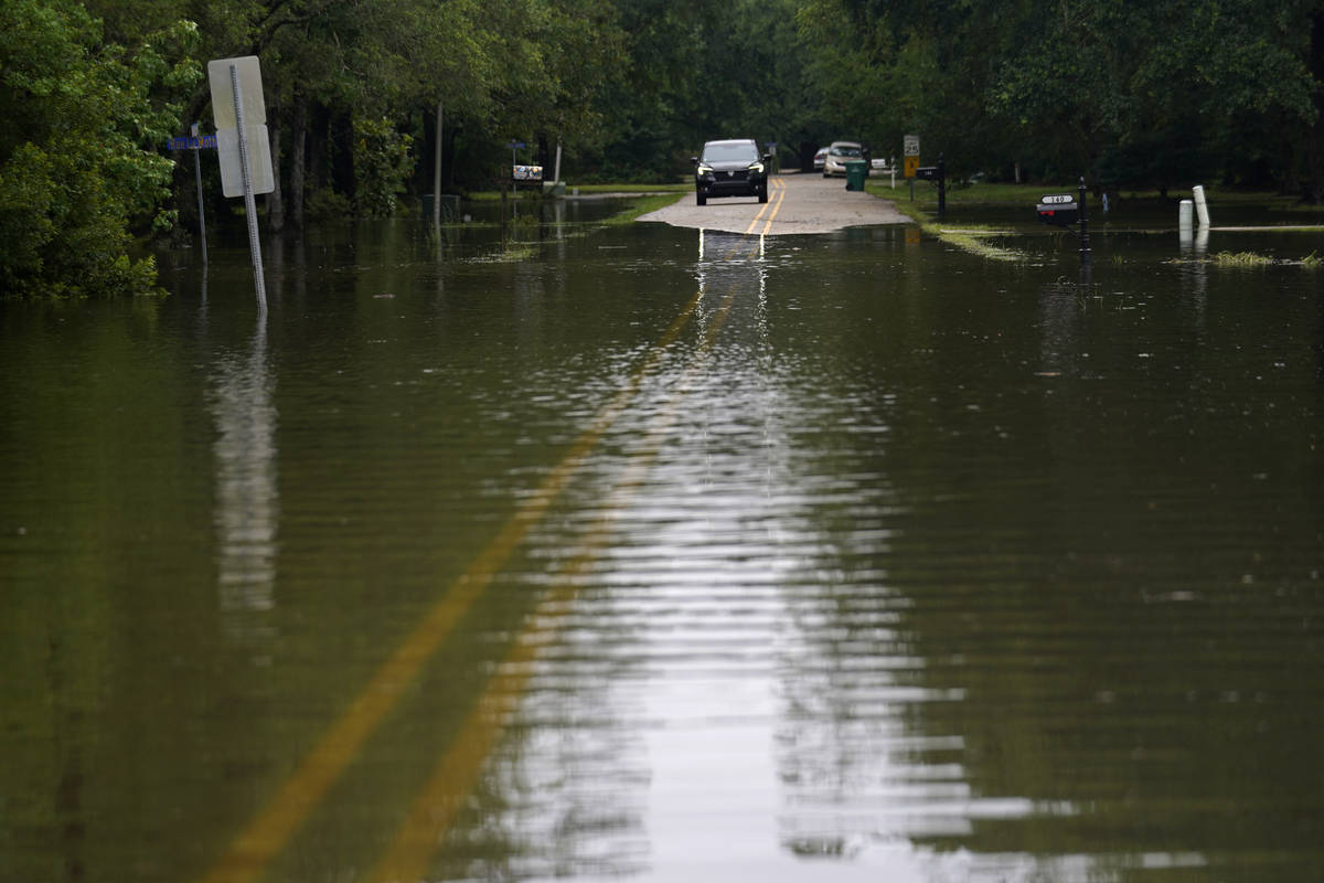A car stops in front of neighborhood flooding after Tropical Storm Claudette passed through, in ...